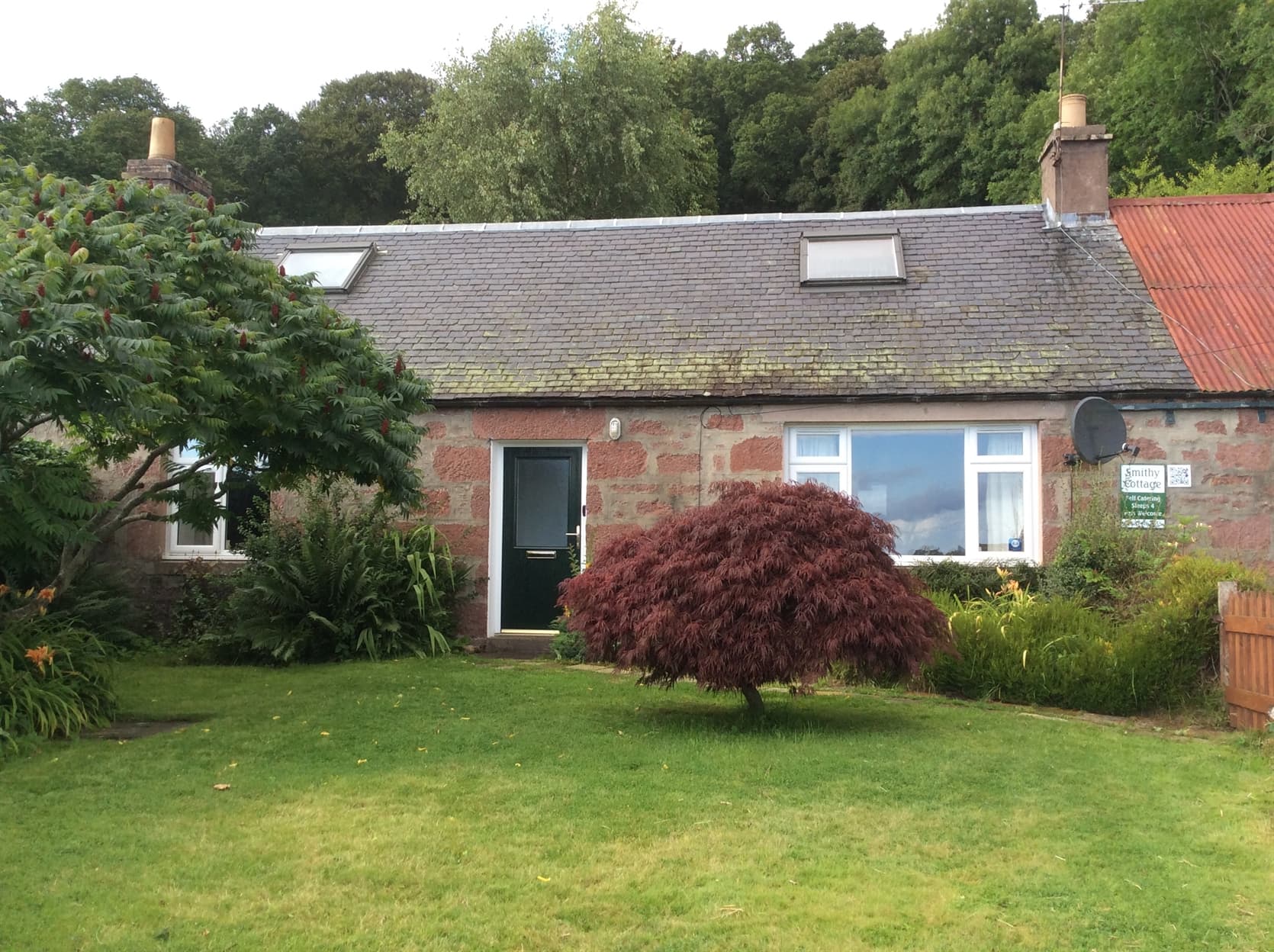 View of front of Smithy Cottage, traditional red sandstone stone cottage